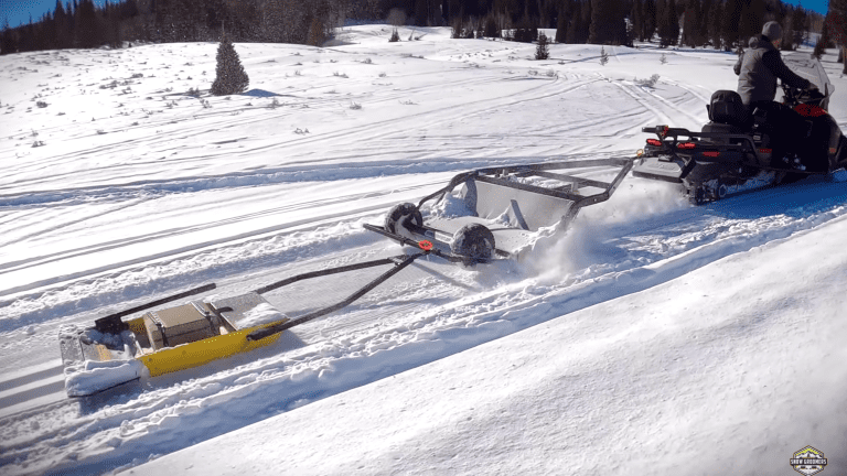 Snowmobile busting powder while laying classic ski track