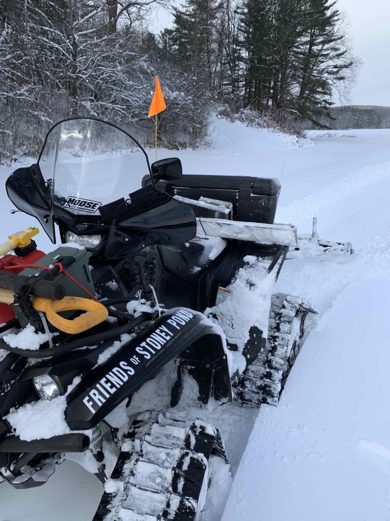 Snowmobile set up to tow a snow groomer on a winter trail